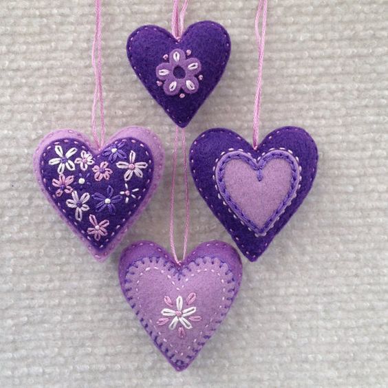 three purple heart ornaments hanging from strings