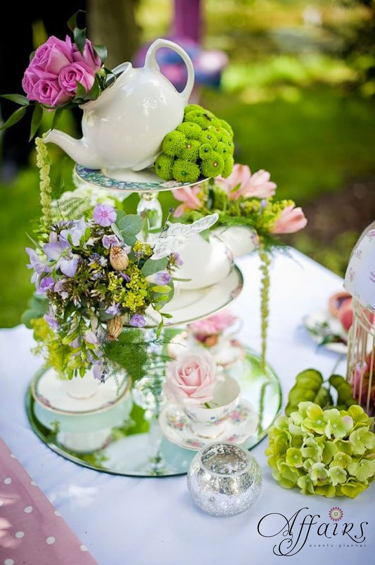 a table topped with vases filled with flowers and greenery next to an empty jar