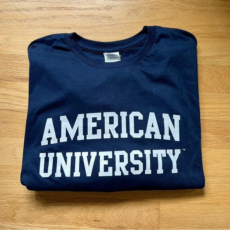 Nwot American University Tee 100% Pre-Shrunk Cotton Fan Apparel Cotton T-shirt For Campus, Navy Pre-shrunk Cotton T-shirt, Navy Cotton Top For College, Navy Cotton Tops For College, Navy Cotton Fan Apparel Tops, Navy Cotton Screen Print Top, Blue Cotton T-shirt With Text Print, Navy Cotton Tops With Logo Print, Collegiate Cotton T-shirt For Campus