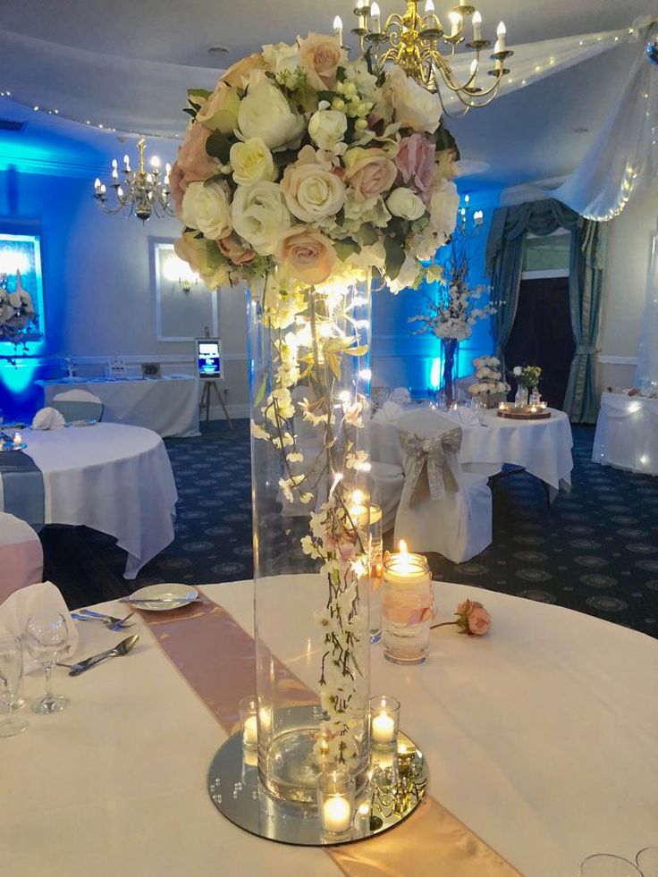 a tall vase filled with lots of flowers on top of a table