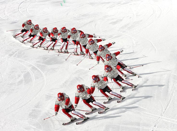 a group of people riding skis down a snow covered slope in the shape of a heart