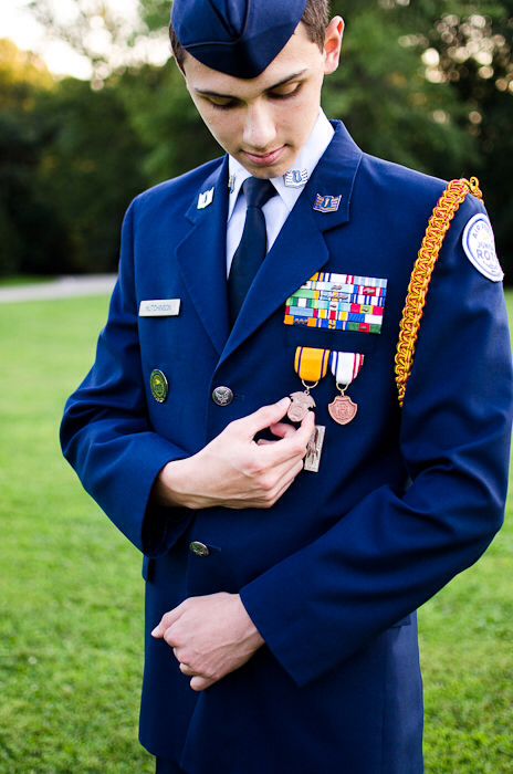 a young man in uniform is looking down at his medal while standing on the grass