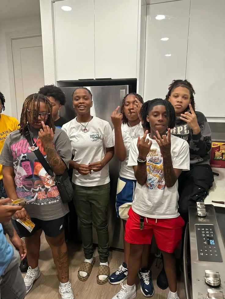 a group of young people standing next to each other in front of an open refrigerator