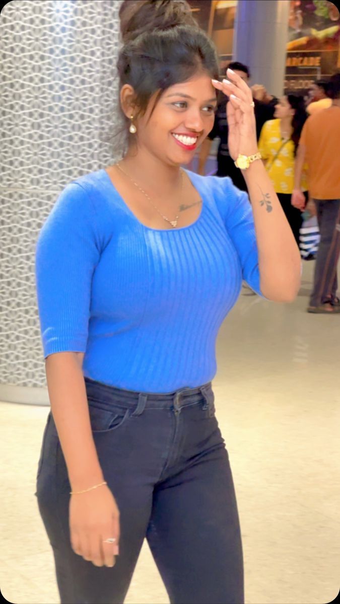 a woman in blue shirt standing next to a wall