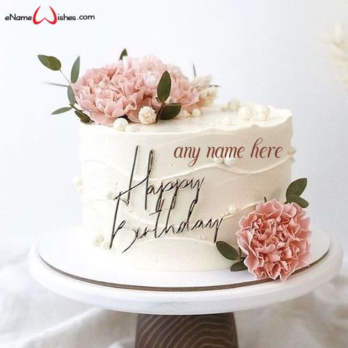 a white cake with pink flowers on top and happy birthday written on the side next to it