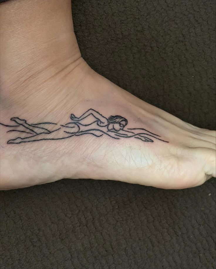 a woman's foot with a tattoo of a person swimming on the ocean waves