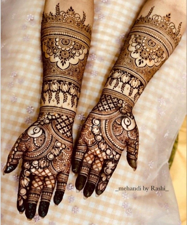 two hands with henna tattoos on them, one is showing the intricate pattern and the other