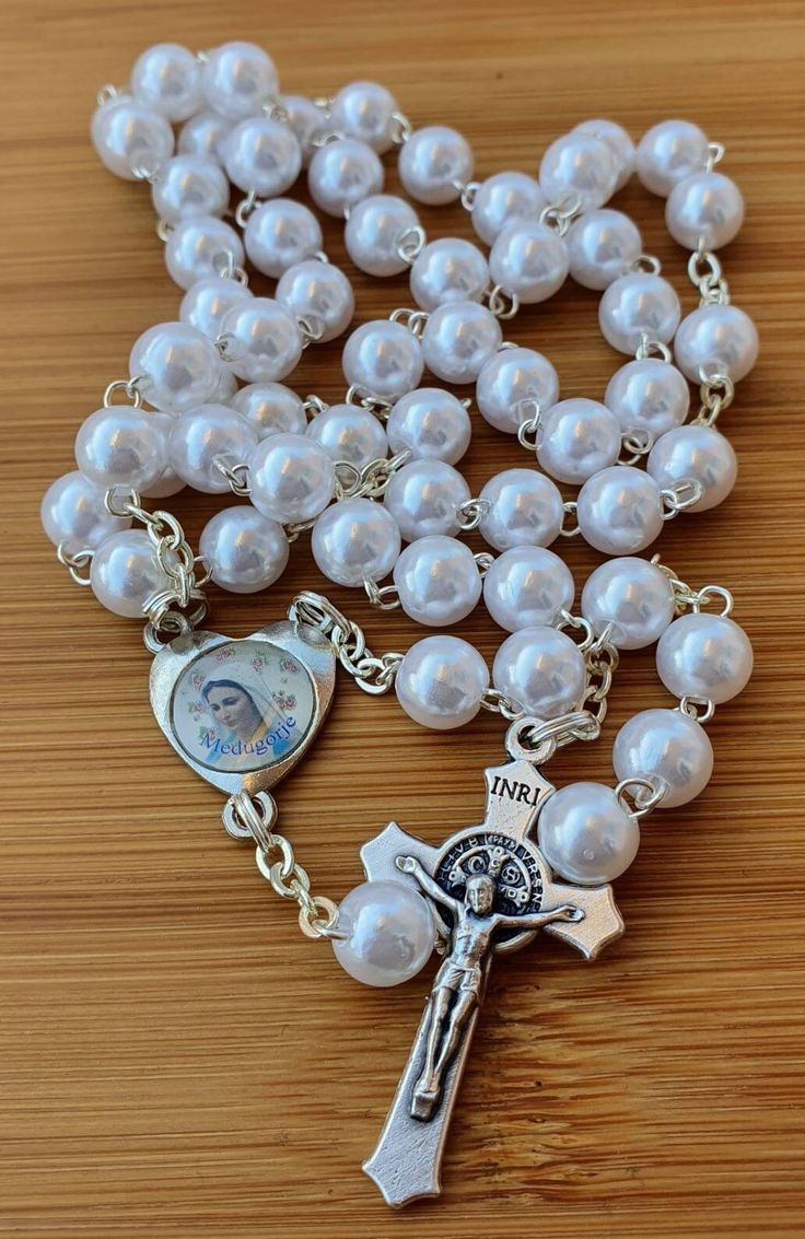 Handmade rosary. Made with silver metal wire and white pearls. This rosary is perfect gift for many occasions, birthday, easter, confirmation, first communion,wedding... Its made with medal Virgin Mary in hearts and cross Saint Benedict. Beads size: 8 mm Beads color: white pearls Rosary lenght 51 cm (20 inch) Cross lenght 3.8 cm ( 1.5 inch) You can choose between 6 models of orders. You can order rosary with your own name, mams name, dads name, or whole family, mam, dad, children, frends name... White Crucifix Rosary With Miraculous Medal, Personalized Silver Rosary For Confirmation, White Spiritual Rosary With Miraculous Medal, Spiritual White Rosary With Miraculous Medal, Pearl Rosary With 8mm Beads As Gift, Pearl Rosary With Round Beads As Gift, Pearl White Rosary With 8mm Beads As Gift, Spiritual Pearl Rosary As Gift, White Pearl Rosary As A Gift