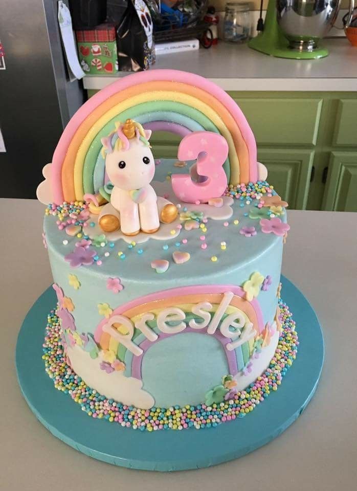 a birthday cake with a unicorn on top and rainbow decorations around the edges, sitting on a kitchen counter