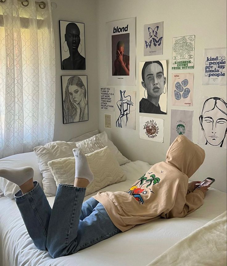 a person laying on top of a white bed in a room with pictures hanging on the wall