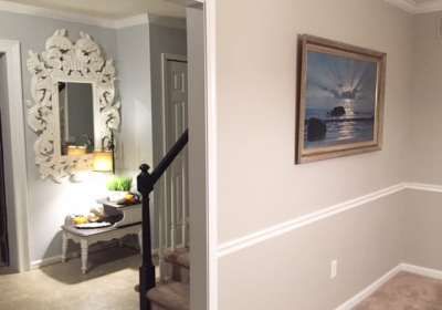 an entry way leading to a living room and dining room area with paintings on the walls