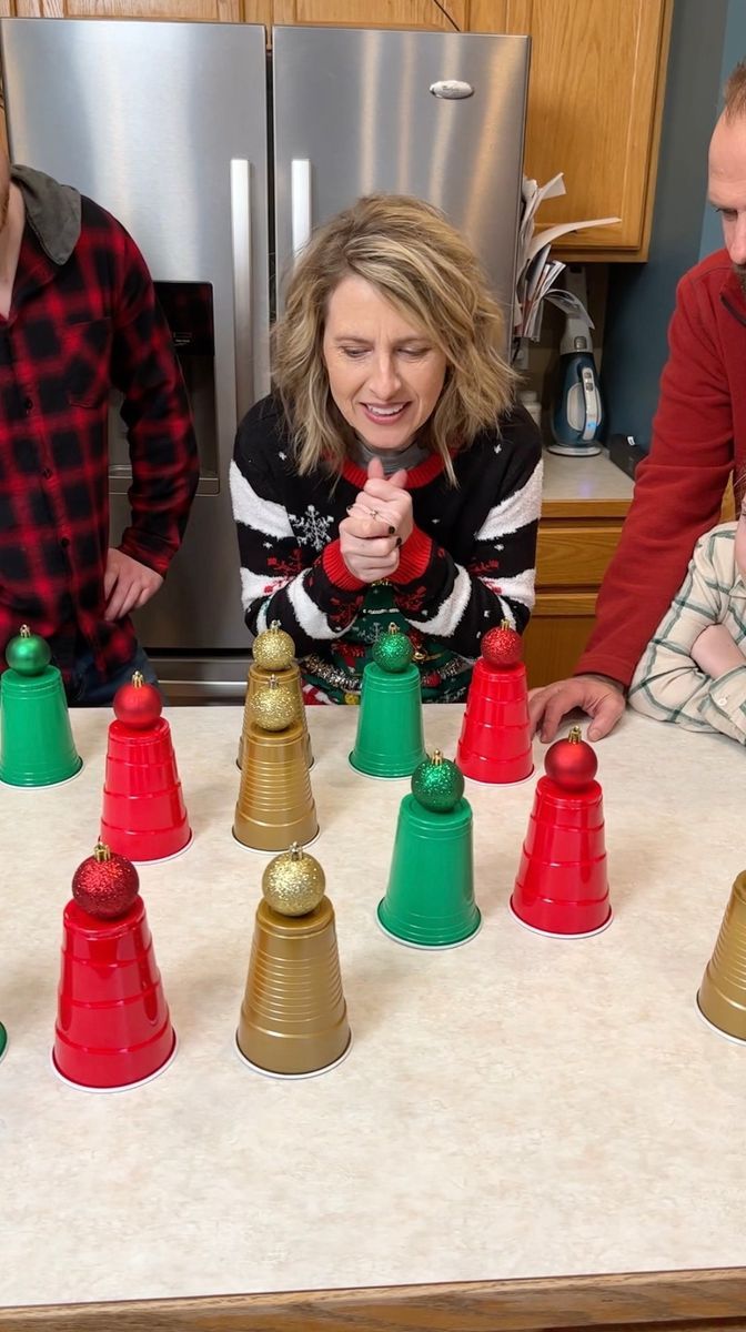 a group of people standing around a table with christmas decorations on it and cups in front of them