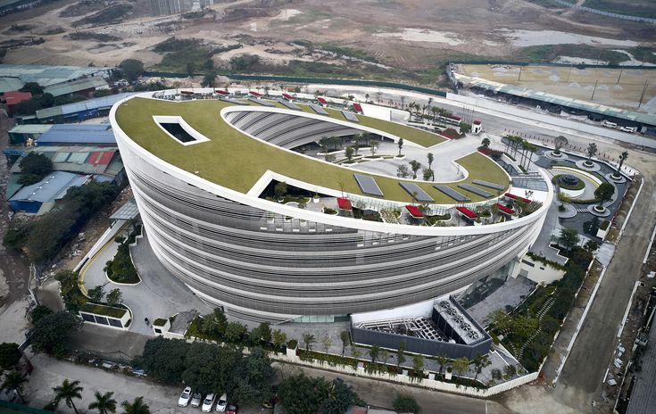 an aerial view of a circular building in the middle of a city with lots of green roofing