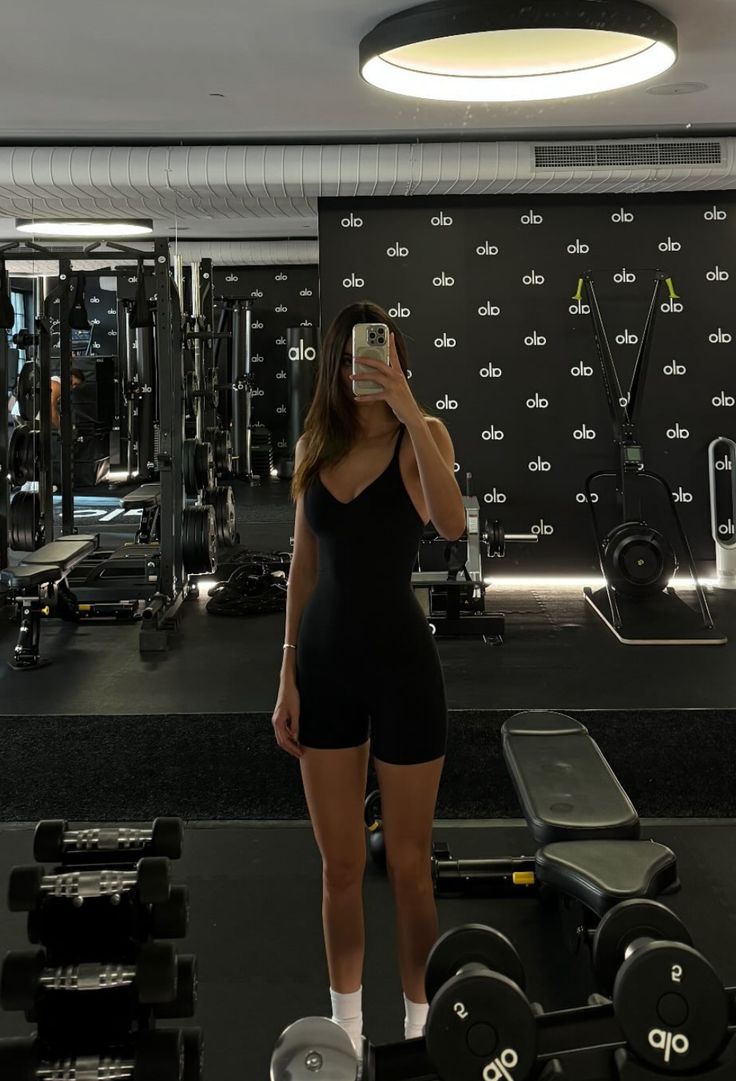 a woman taking a selfie in the gym with her phone up to her ear