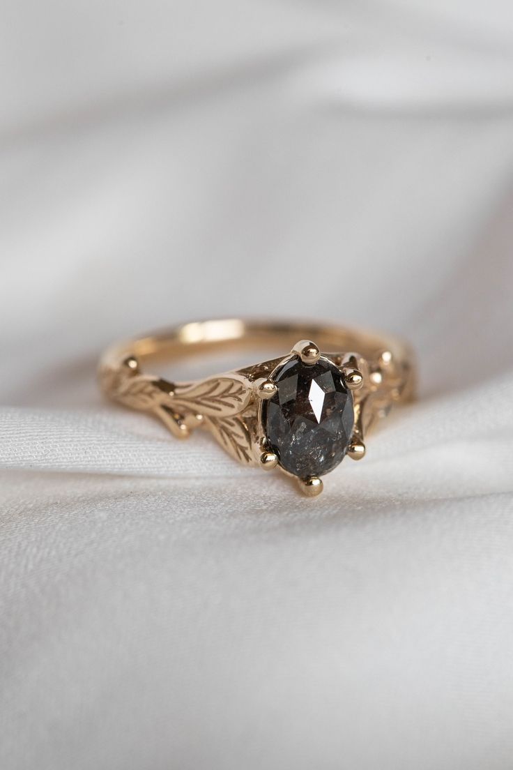 a gold ring with a black diamond in it on a white cloth background, close up