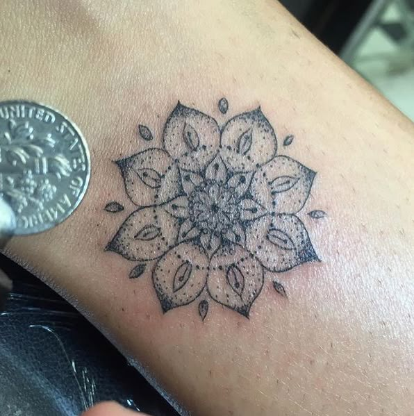 a woman's arm with a tattoo on it that has a flower in the center