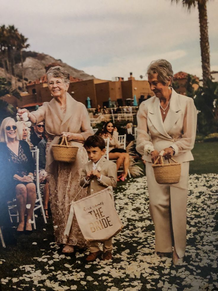 an old photo of two women and a young boy holding baskets with flowers on them