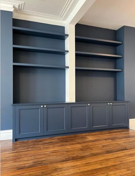 an empty room with blue bookcases and wood floors