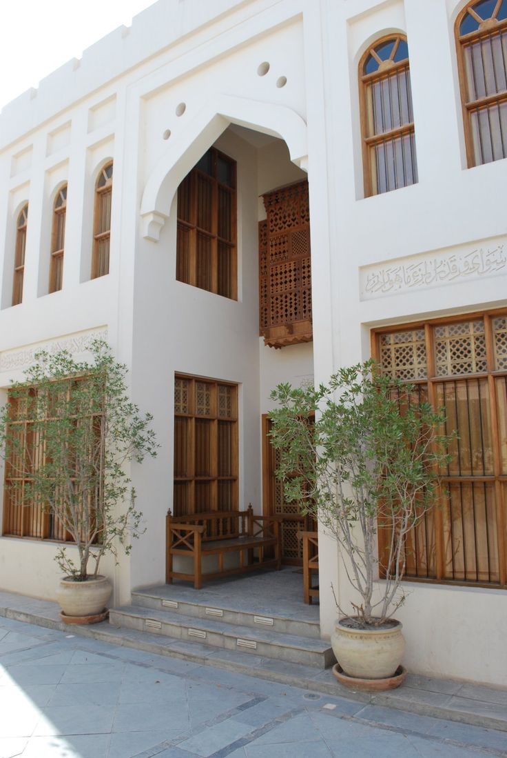 the building has many windows and wooden shutters on it's sides, along with potted trees