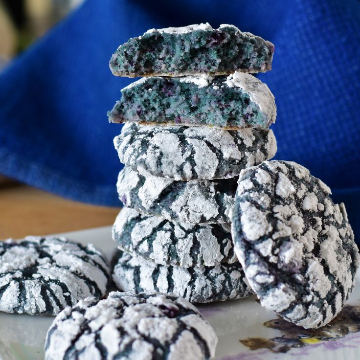 a pile of cookies sitting on top of a white plate covered in powdered sugar