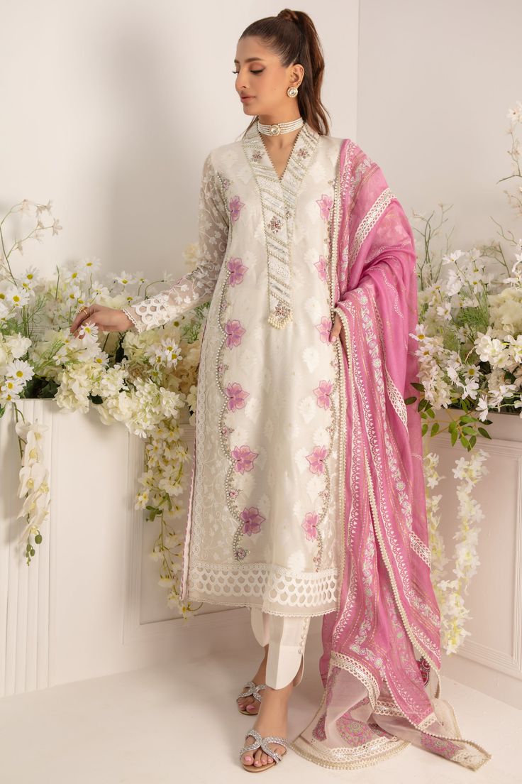 Design to shine on Eid festivities, this ensemble features stunning silk thread & applique work further enhanced with pearls, sequins & beadwork. Aari embroidered sleeves & side panels, stylish lace & embroidered border incorporated sleeves. This outfit is paired with hand Block printed statement and dupatta with lace & gota trims all over paired with straight pants with button details. Shirt Fabric: Pure Jacquard Silk net & embroidered Silk net Shirt Length: 48” (customisable, mention in order Net Shirt, Designer Outfit, Applique Work, Embroidered Sleeves, Embroidered Border, Pakistani Designers, Silk Dupatta, Shine On, Shirt Fabric