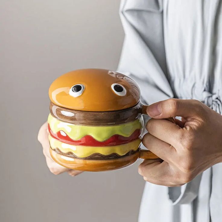 a woman is holding a hamburger shaped container