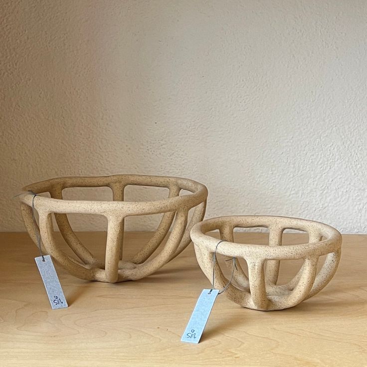 two wooden bowls sitting on top of a table next to each other with price tags in front of them