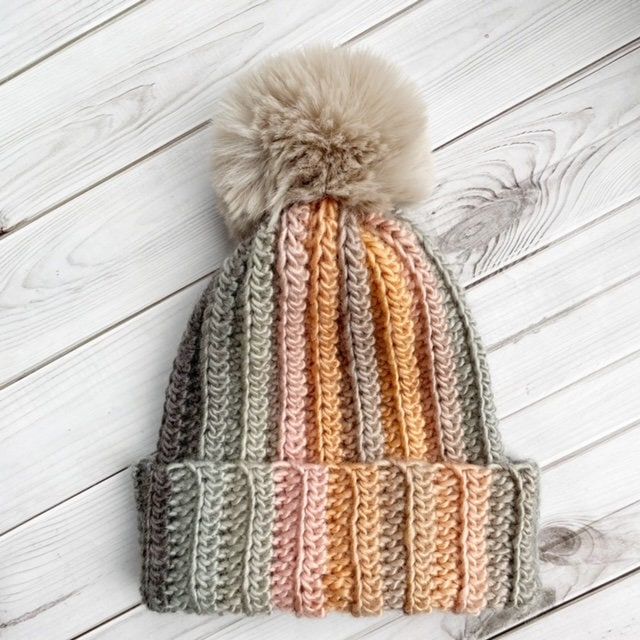 a multicolored knitted hat with a pom - pom on top