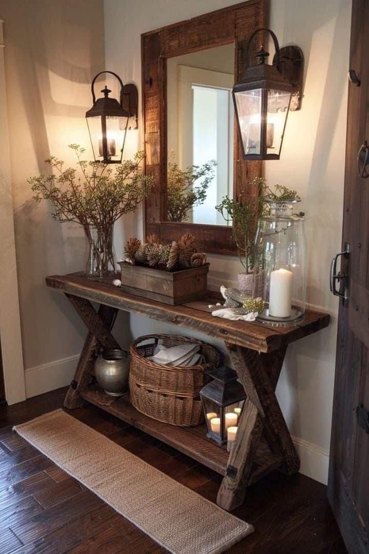 a wooden table topped with vases filled with flowers next to a wall mounted mirror