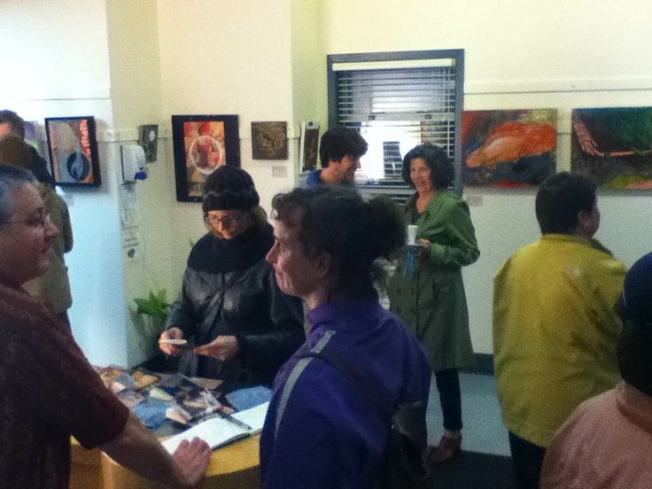 a group of people standing around each other in a room with pictures on the wall