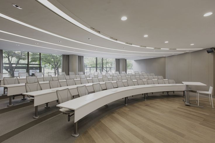 an empty conference room with white chairs and tables in the center, along with large windows