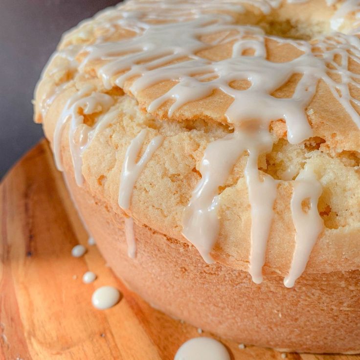 a cake with white icing sitting on top of a wooden cutting board