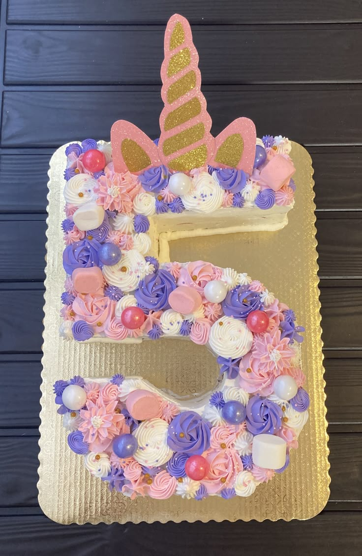 a birthday cake that is shaped like the number five with flowers and unicorns on it