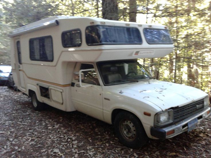 an rv parked in the woods next to a car and truck with its roof up