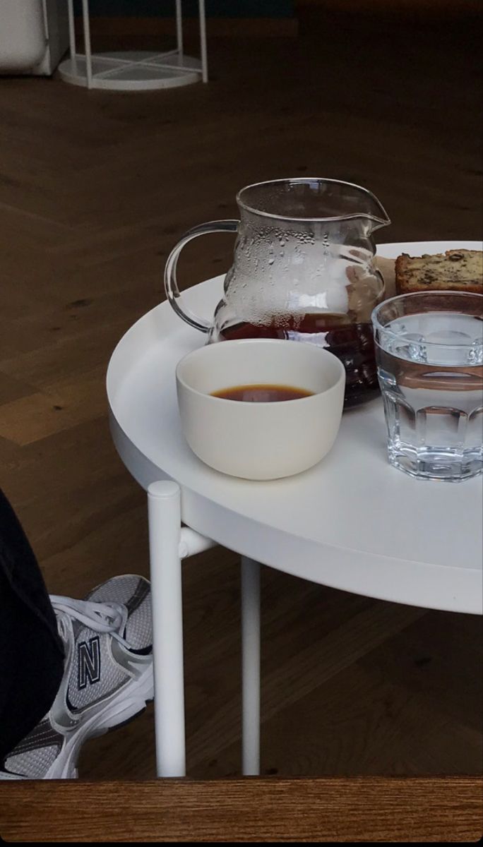 a white table topped with plates and bowls filled with food next to a glass pitcher