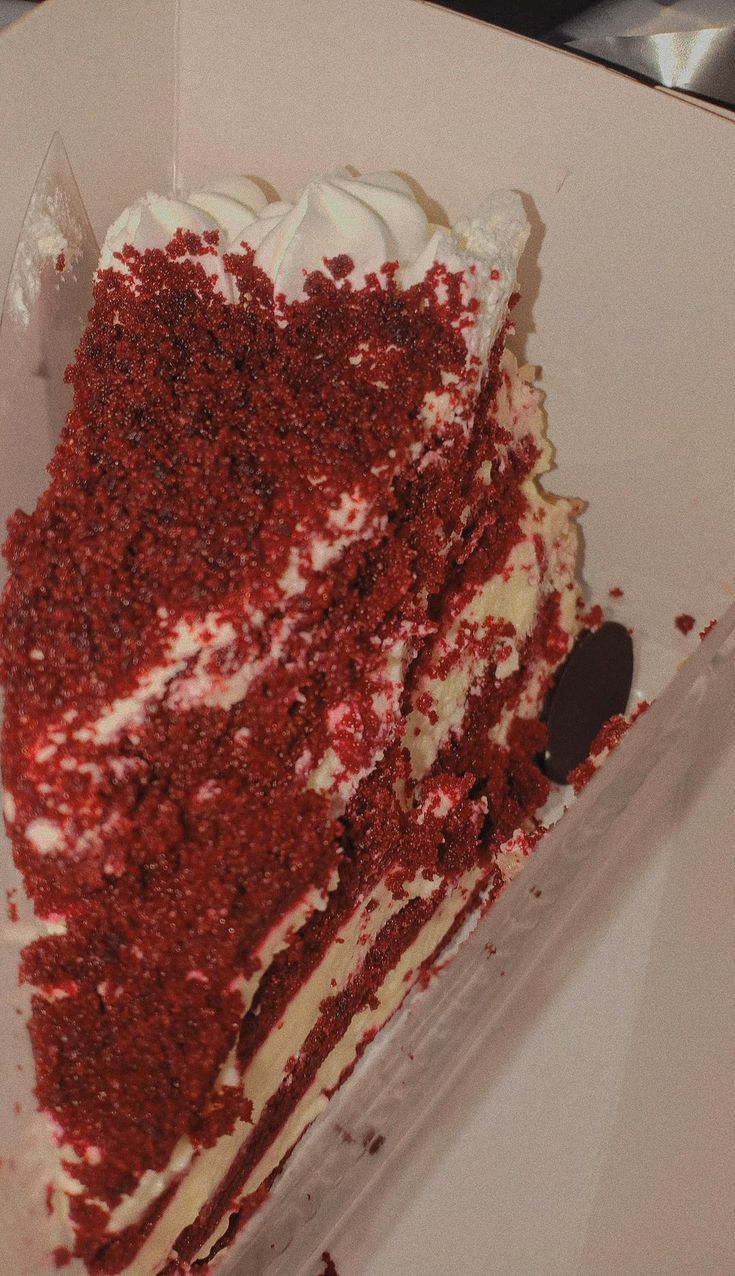 a slice of red velvet cake with white frosting in a box on a table