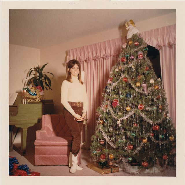 a woman standing next to a christmas tree