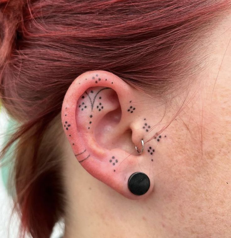 a woman's ear with black dots on it