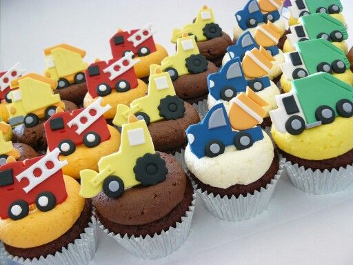 there are many cupcakes with cars and trucks on them, all decorated in different colors