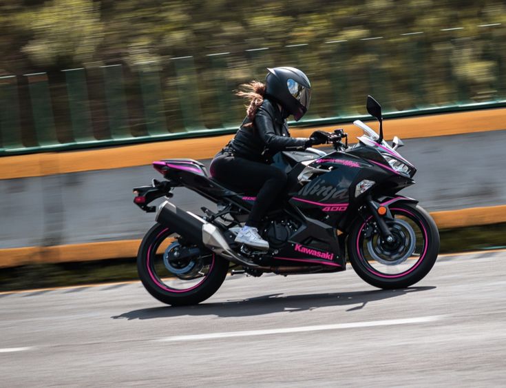 a woman riding on the back of a pink motorcycle