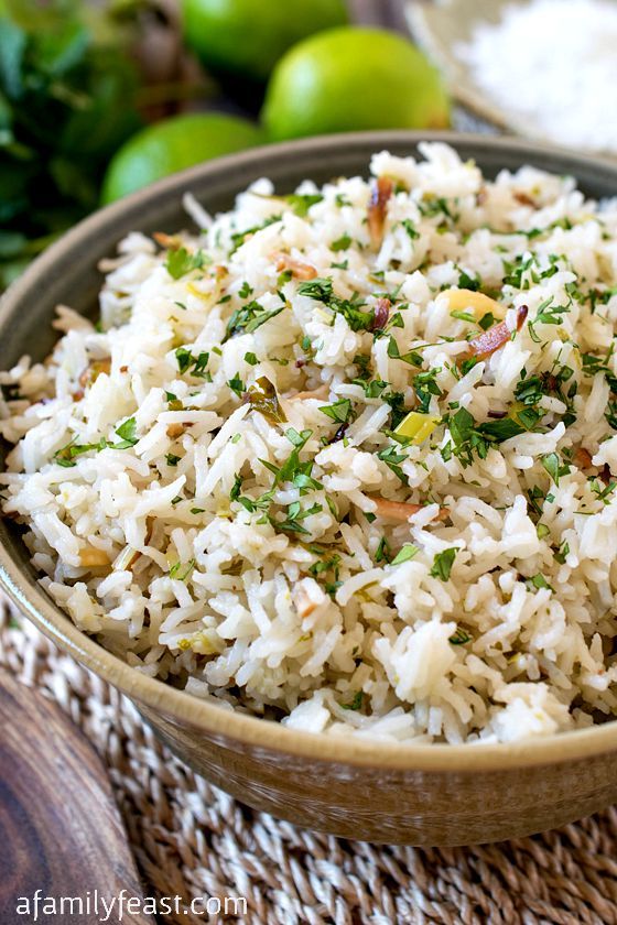 a close up of a bowl of rice on a table with limes in the background