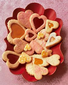 heart shaped cookies in a red bowl on a pink tablecloth with flowers and hearts