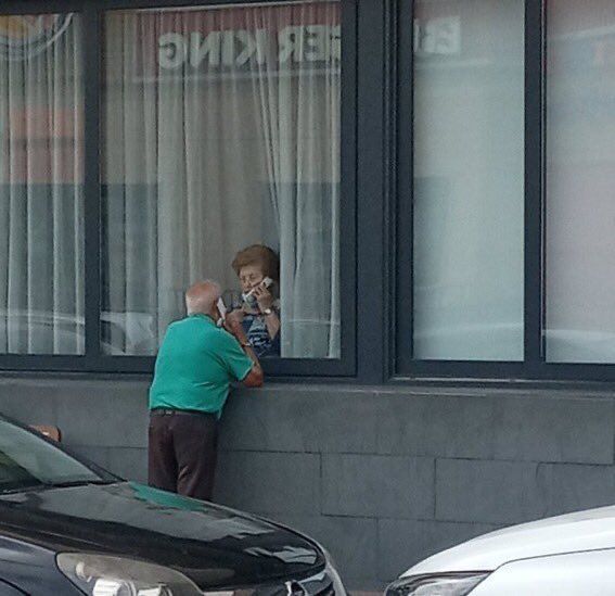 a man standing on the side of a building holding a cell phone to his ear