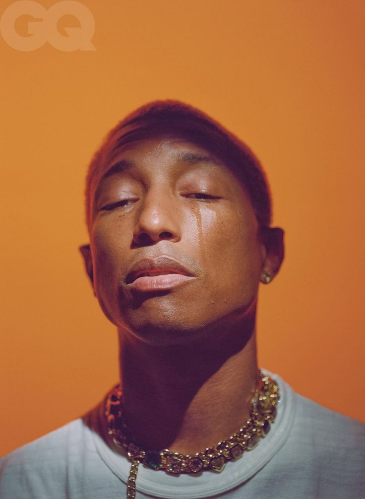 a young man with his eyes closed wearing a necklace and t - shirt against an orange background