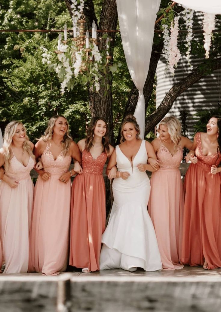 a group of women standing next to each other in front of a white and pink tent