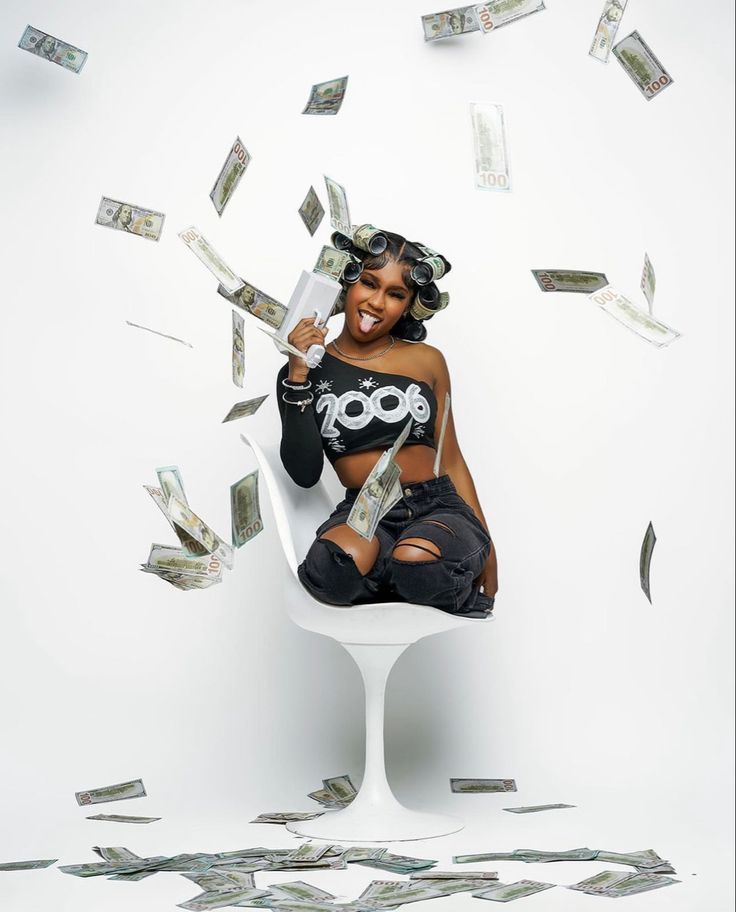 a woman sitting on top of a white chair with money falling from the sky behind her