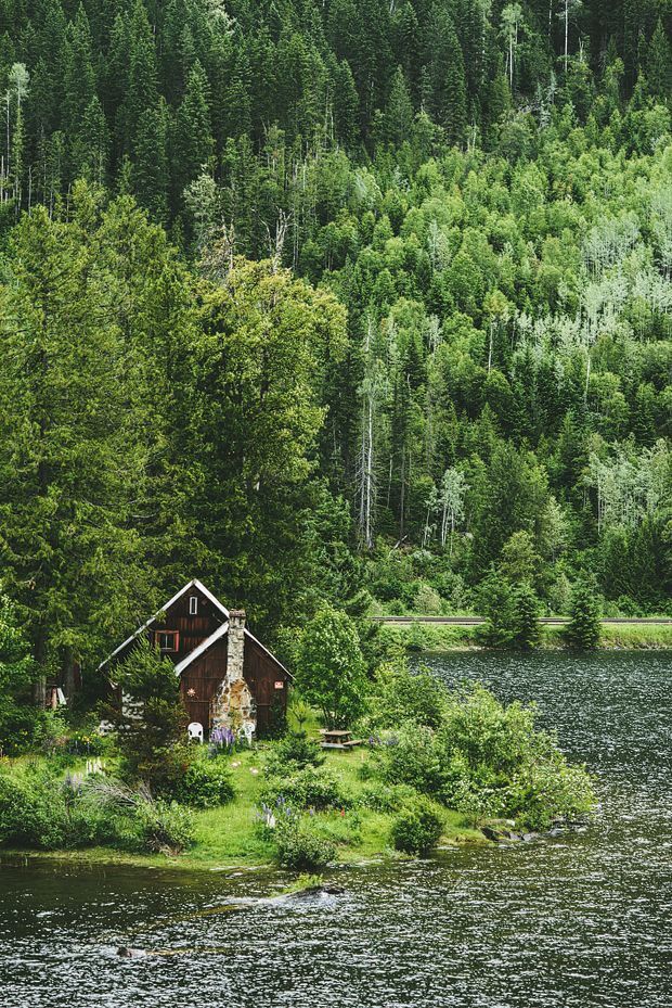 black and white photograph of a cabin in the middle of a lake surrounded by trees