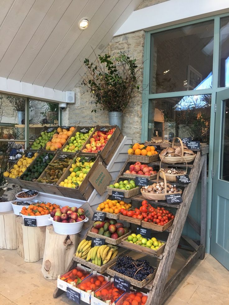 an open air market with lots of fruits and vegetables in bins on the shelves