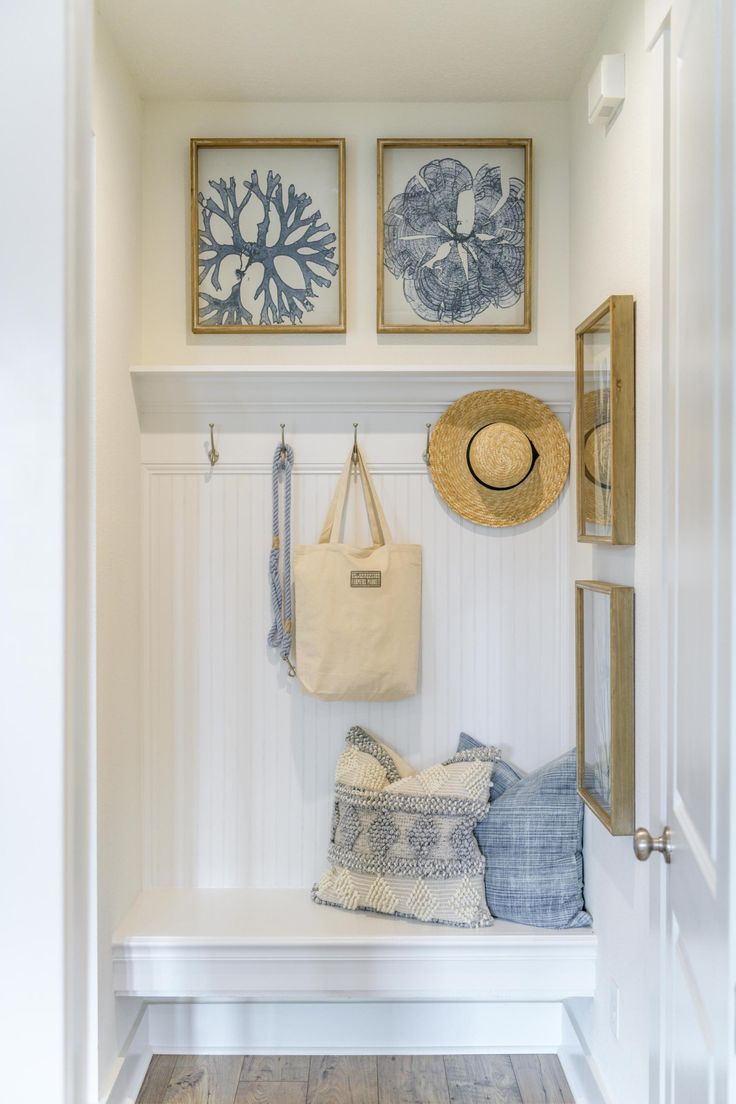 a white bench with two pictures on the wall and a tote bag hanging from it