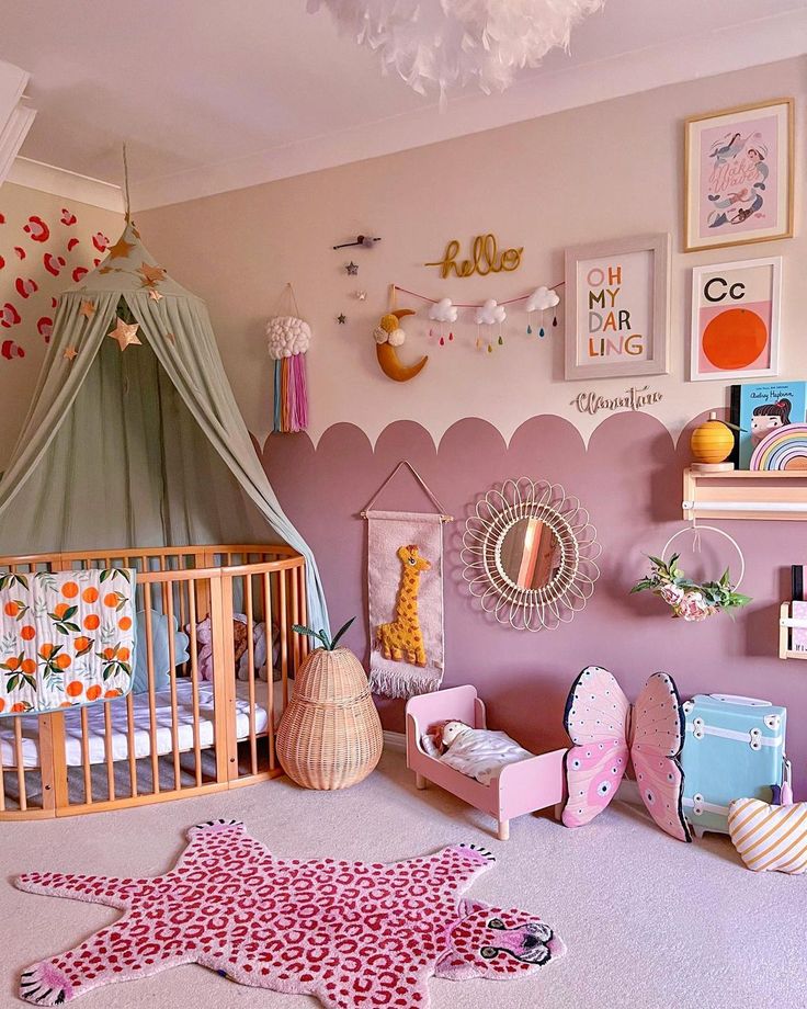 a child's bedroom with pink walls and decorations on the wall, including a crib